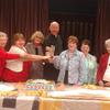 Pastor Paul and the Quilting Club cutting the cake in celebration of their work
